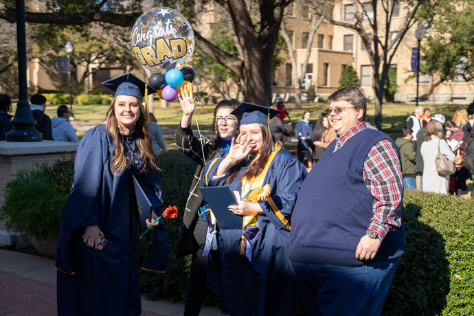 A family taking a photo with a Texas Wesleyan graduate in full cap and gown